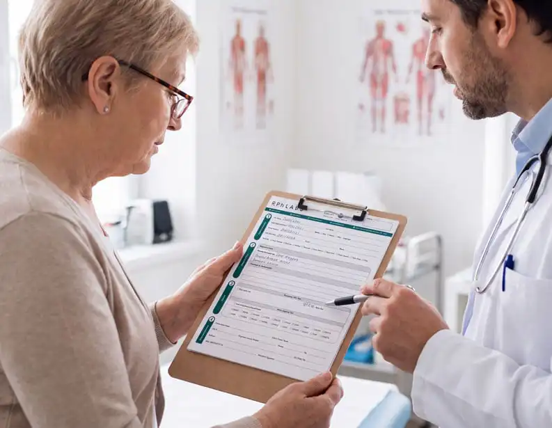 Pharmacist walking a patient through the RPh Labs pharmacogenomic testing form on a clipboard